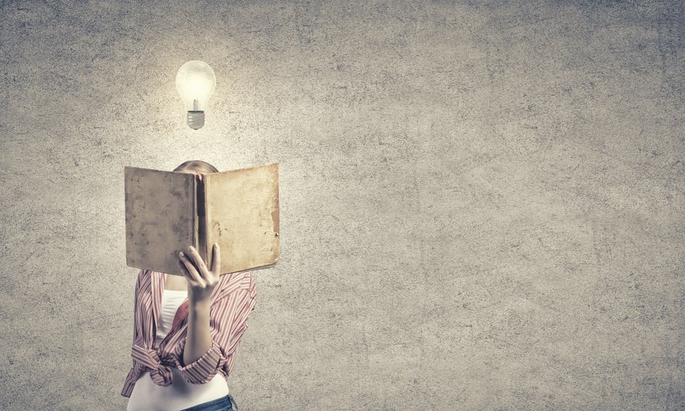 Young funny girl with opened book in hands